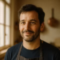 Portrait d'un homme en tablier souriant dans une cuisine.